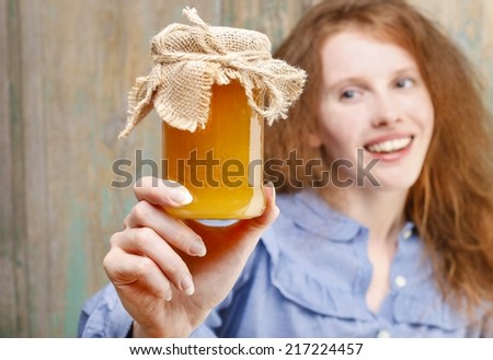 Happy young woman holding glass jar of honey, copy space - stock photo - stock-photo-happy-young-woman-holding-glass-jar-of-honey-copy-space-217224457