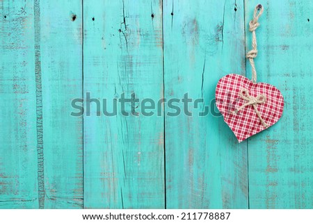 Red checkered heart hanging from rope on antique teal blue wood fence ...