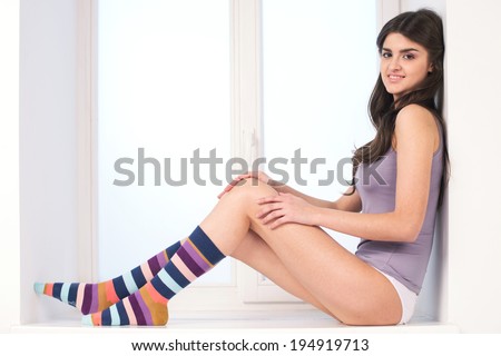 http://thumb101.shutterstock.com/display_pic_with_logo/1672675/194919713/stock-photo-beautiful-young-brunette-sitting-on-window-sill-pretty-lady-wearing-colorful-knee-socks-194919713.jpg