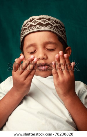 A Muslim boy wearing a traditional hat praying - stock photo - stock-photo-a-muslim-boy-wearing-a-traditional-hat-praying-78238828