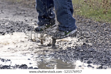 A child's feet as he jumps in to a rain puddle - stock photo