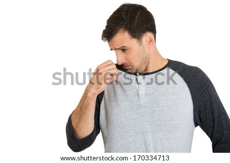 Closeup portrait of young man, smelling, sniffing his armpit ...