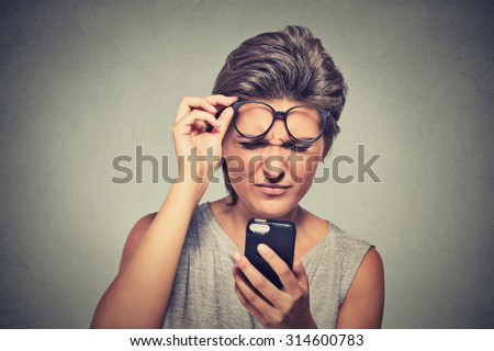 Closeup portrait headshot young woman with glasses having trouble seeing cell phone has vision problems. Bad text message. Negative human emotion facial expression perception. Confusing technology - stock photo