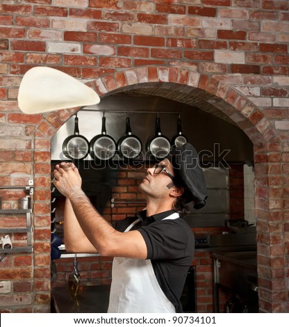 Pizza Chef makes the pizza dough spin in the air to make it thin and soft - stock photo