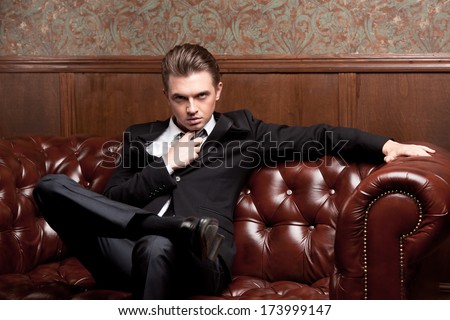 http://thumb101.shutterstock.com/display_pic_with_logo/1287775/173999147/stock-photo-attractive-young-man-in-a-suit-sitting-on-a-retro-couch-173999147.jpg