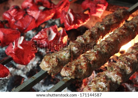 cooked indian chicken tikka shish kofte kebabs on flaming barbecue - stock photo
