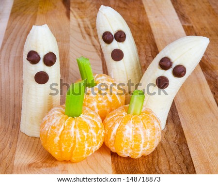 Halloween child friendly treats with bananas and clementines made to look like pumpkins and ghosts - stock photo