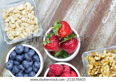 Healthy snack foods with small bowls of raspberries, blueberries, strawberries, cashews and walnuts - stock photo