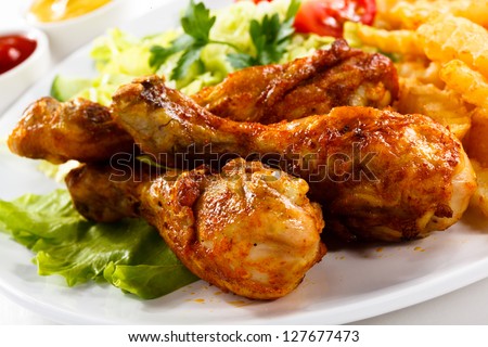 Grilled chicken legs with chips and vegetables - stock photo