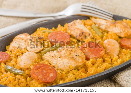 Paella Valenciana - Traditional Valencian paella with white rice, chicken, sausage, butter beans and green vegetables. - stock photo