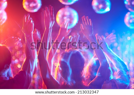 Crowd of young people dancing in night club - stock photo